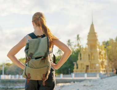 Young woman looking at golden pagoda. Hiking at Asia