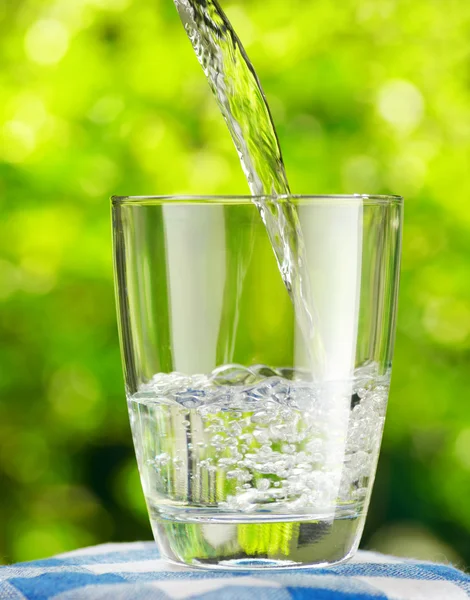 Glas water op aard achtergrond — Stockfoto