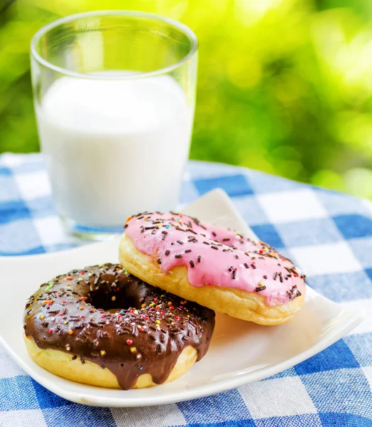 Donuts frescos y vaso de leche en el fondo de la naturaleza —  Fotos de Stock