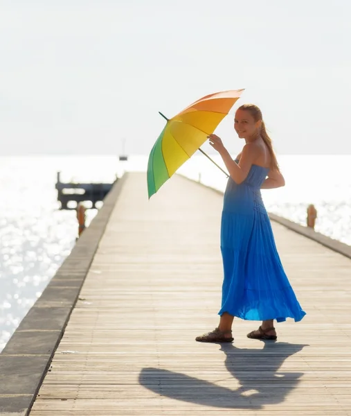 Young woman walking on the pier with umbrella — Stock Photo, Image