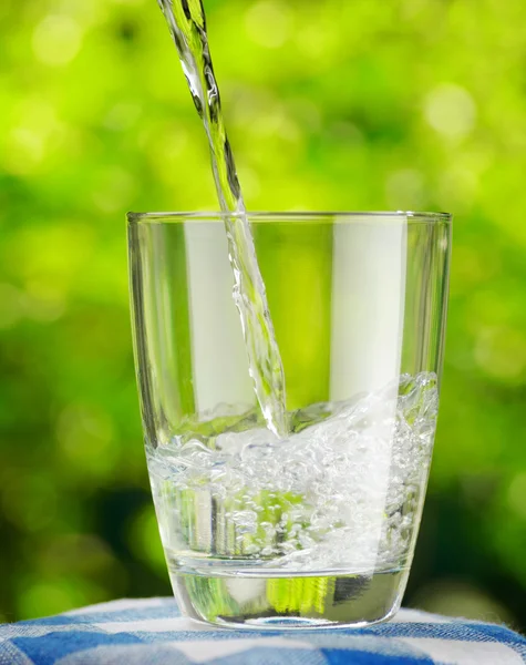 Glas water op aard achtergrond — Stockfoto