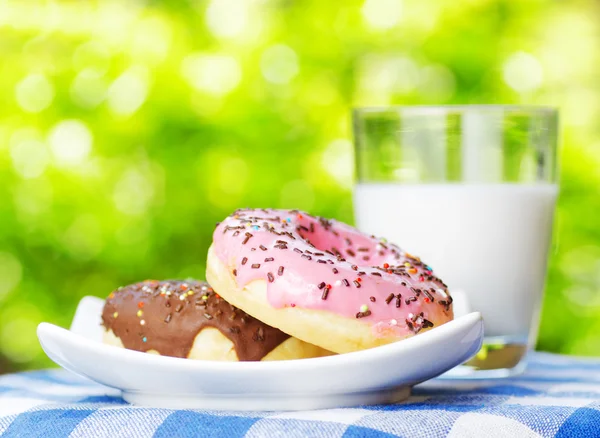 Frische Donuts und ein Glas Milch auf Naturhintergrund — Stockfoto