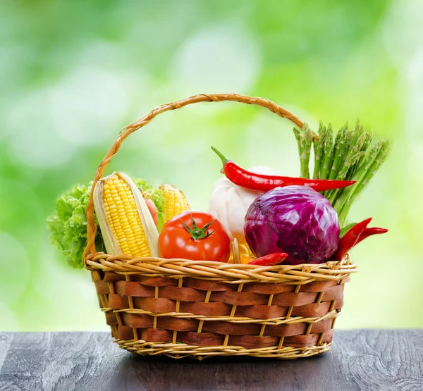 Färska grönsaker i korgen på träbord — Stockfoto