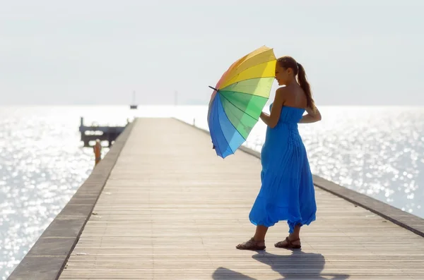 Mladá žena chůze po molu s deštníkem — Stock fotografie