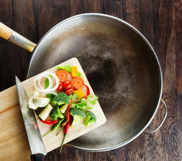 Las verduras frescas en la tabla de cortar están cayendo en el wok. Co — Foto de Stock