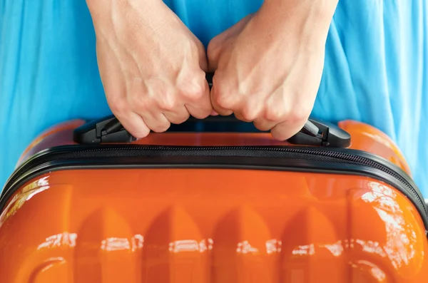 Woman in blue dress holds orange suitcase in hands — Stock Photo, Image