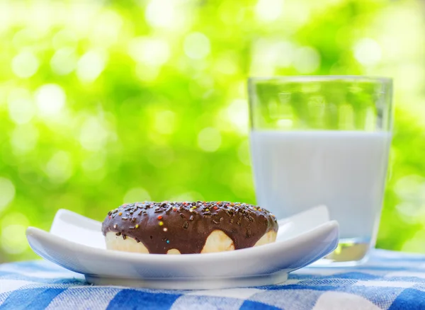 Beignet frais et verre de lait sur fond nature — Photo