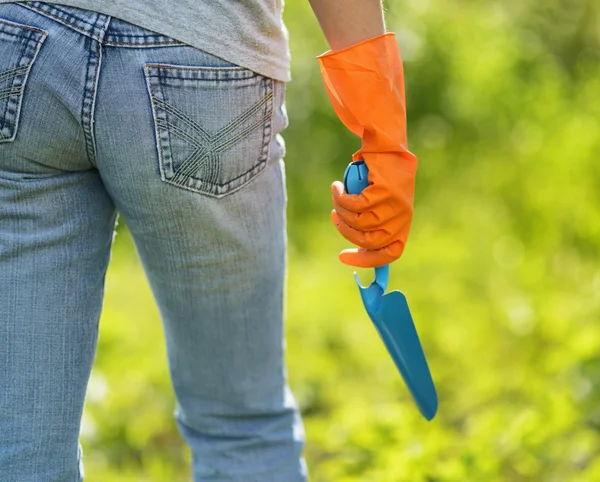 Mujer con guantes naranja trabajando en el jardín — Foto de Stock