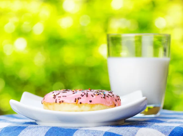 Fresh donut and glass of milk on nature background — Stock Photo, Image