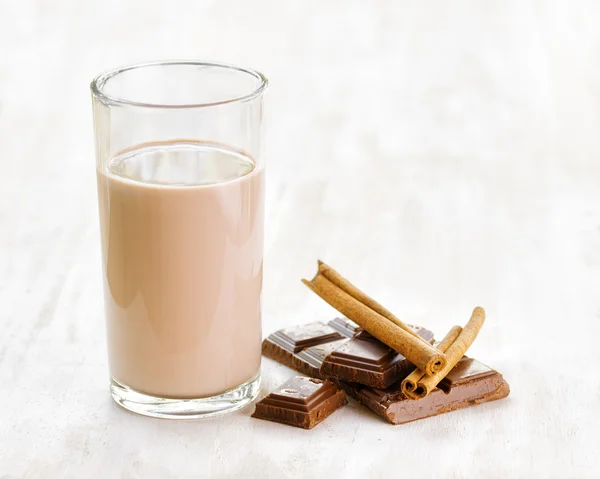 Шоколадное молоко с шоколадом и корицей на белом деревянном столе — стоковое фото