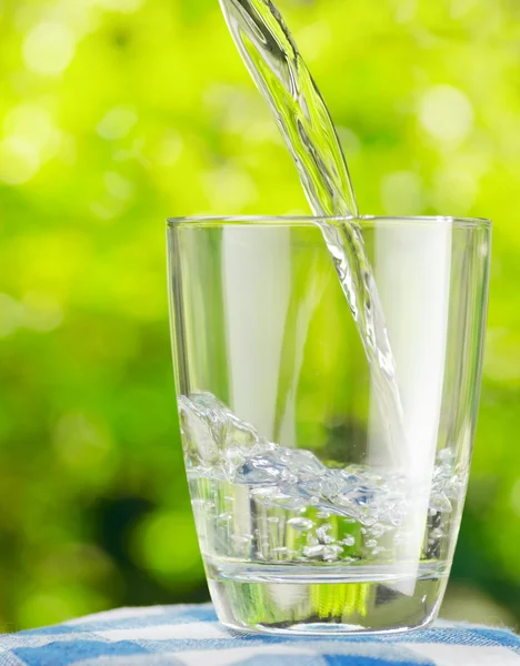 Glas water op aard achtergrond — Stockfoto