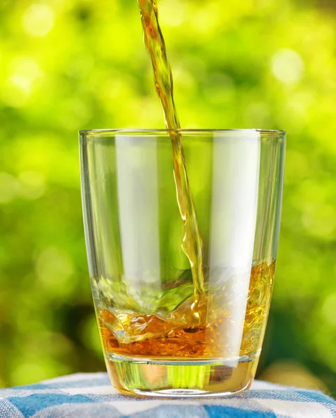 Склянка яблучного соку на фоні природи — стокове фото