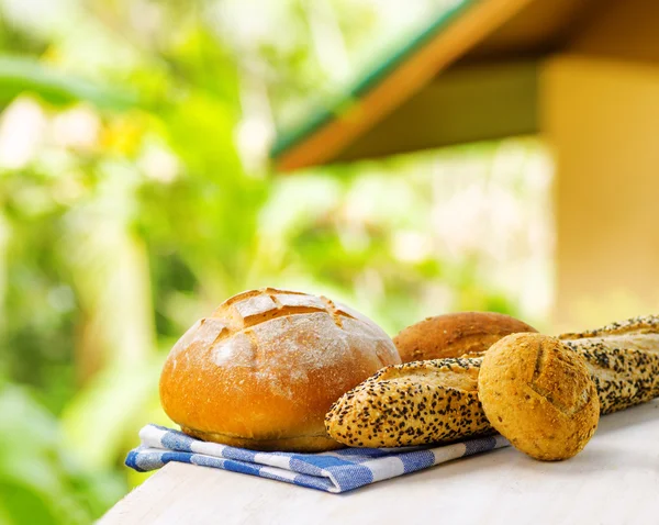 Fresh bread and checkered napkin on wooden table on rural backgr — Stock Photo, Image