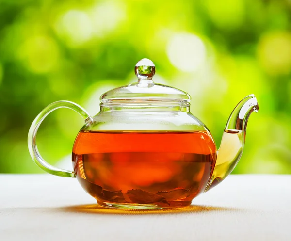 Teekanne mit frischem Tee auf natürlichem Hintergrund — Stockfoto