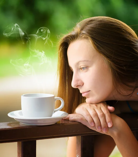 Una joven bebiendo cofee en un jardín. Retrato al aire libre — Foto de Stock