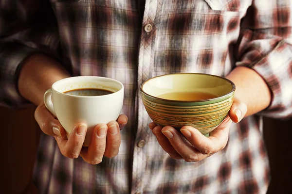 Старшая женщина держит чашку кофе и чашку чая — стоковое фото