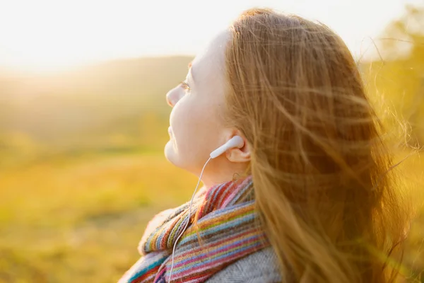 Ung kvinna njuter en musik i höstsäsongen. hösten utomhus — Stockfoto