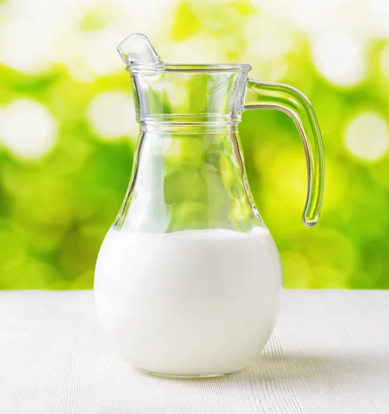 Caraffa di latte su sfondo naturale. Brocca mezza piena — Foto Stock