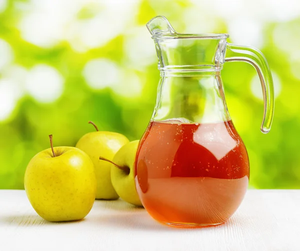 Jug of apple juice on nature background — Stock Photo, Image