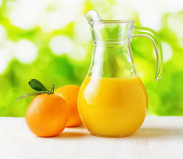 Jug of orange juice on nature background — Stock Photo, Image