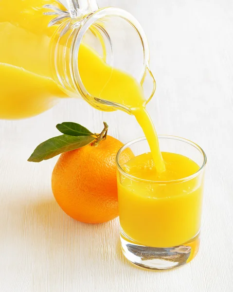 एक टेबल पर नारंगी रस का ग्लास — स्टॉक फ़ोटो, इमेज