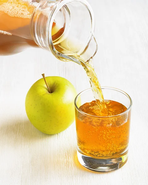 Gieten van kruik in een glas appelsap — Stockfoto