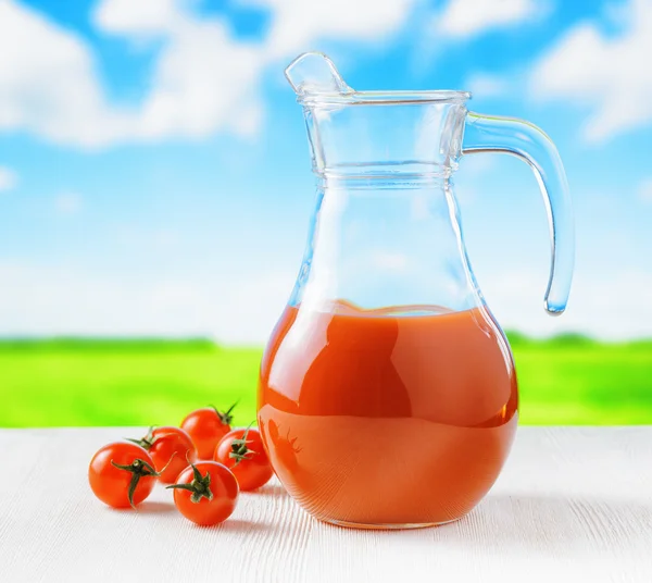 Jarra de jugo de tomate sobre fondo natural. Mitad jarra llena —  Fotos de Stock