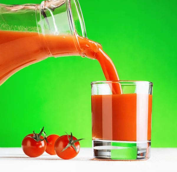 Tomato juice pouring from jug into a glass — Stock Photo, Image