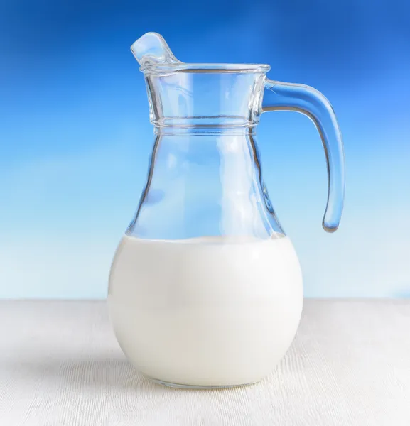 Caraffa di latte su sfondo cielo. Brocca mezza piena — Foto Stock