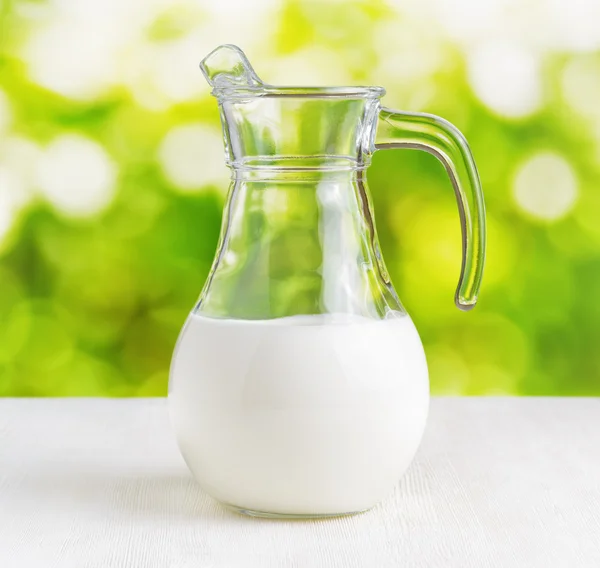 Caraffa di latte su sfondo naturale. Brocca mezza piena — Foto Stock