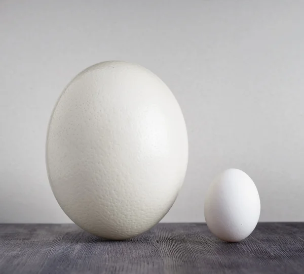 Ostrich egg and chicken egg on black table — Stock Photo, Image