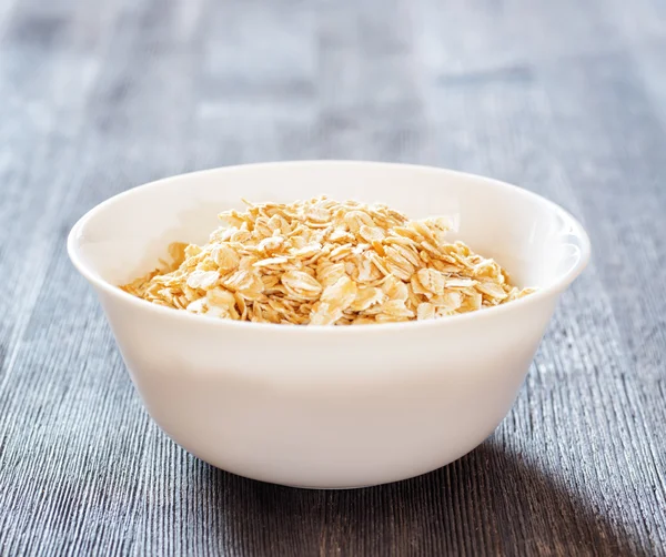 Cuenco de avena sobre mesa de madera — Foto de Stock