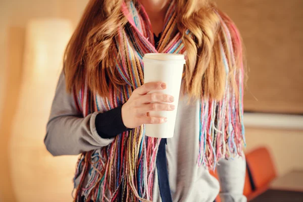 Ung kvinde holder en tørretumbler af kaffe i cafe - Stock-foto