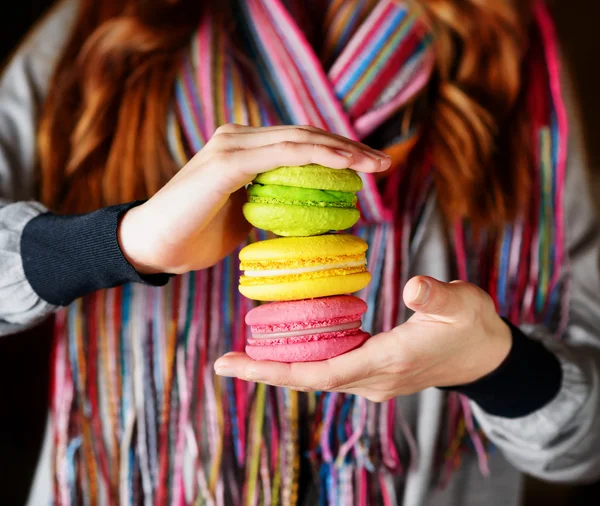 Mujer joven sosteniendo la pastelería francesa macaron en la cafetería — Foto de Stock