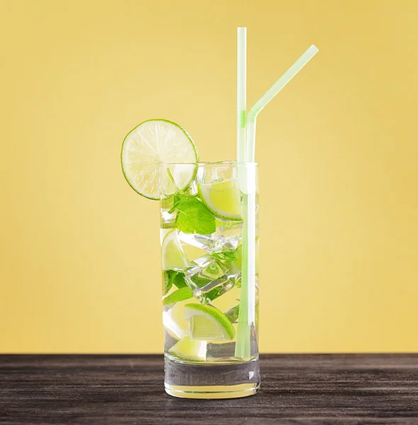 Glass of mojito cocktail on pastel yellow background — Stock Photo, Image