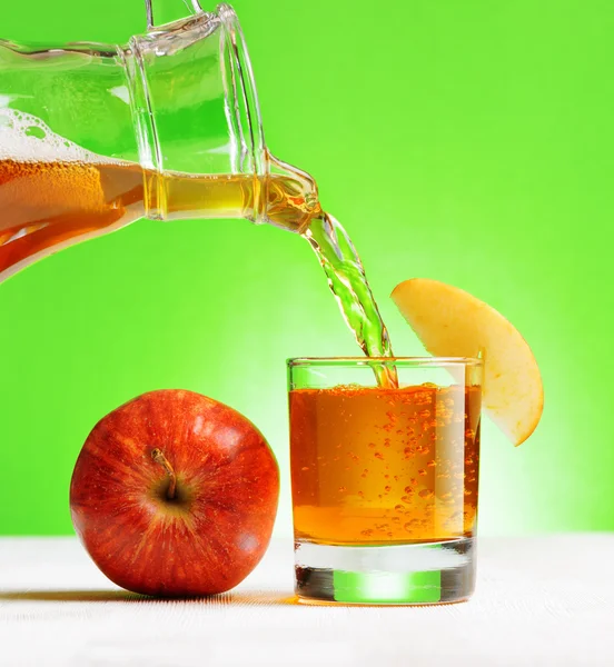 Sumo de maçã que despeja do jarro em um copo — Fotografia de Stock