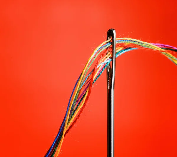 Several colourful threads in a needle — Stock Photo, Image