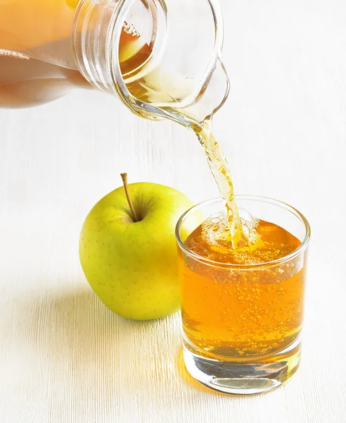 Gieten van kruik in een glas appelsap — Stockfoto