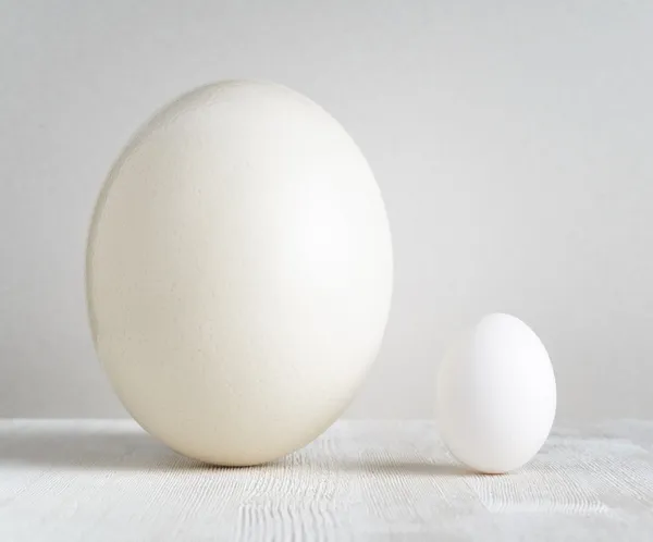 Devekuşu yumurta ve tavuk yumurta beyaz masa üzerinde — Stockfoto