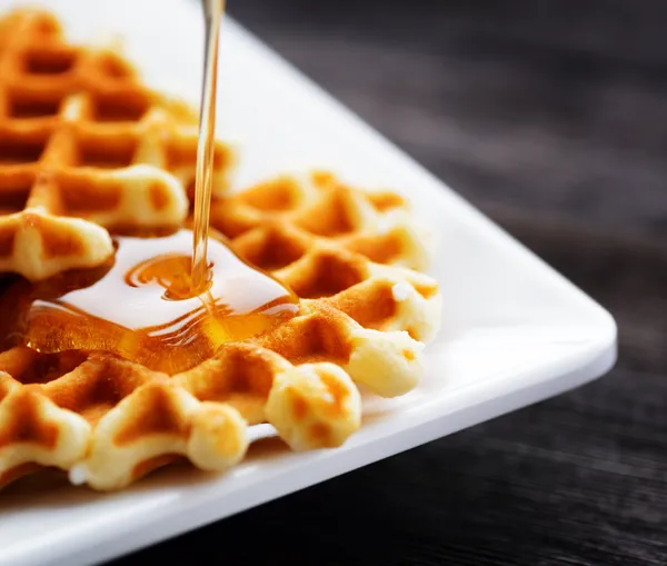 Honey pouring on a fresh waffles — Stock Photo, Image
