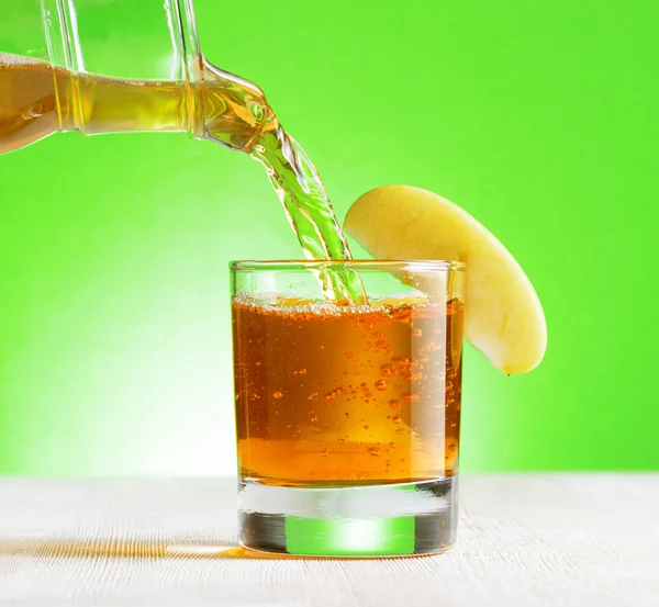 Gieten van kruik in een glas appelsap — Stockfoto