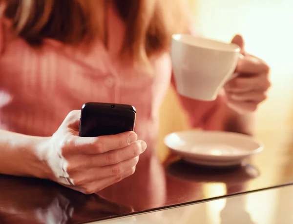 Młoda kobieta za pomocą smartfona w kawiarni — Zdjęcie stockowe