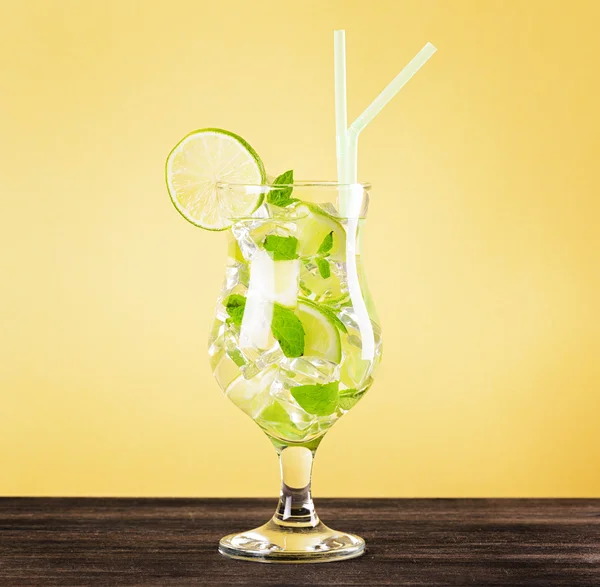 Glass of mojito cocktail on pastel yellow background — Stock Photo, Image