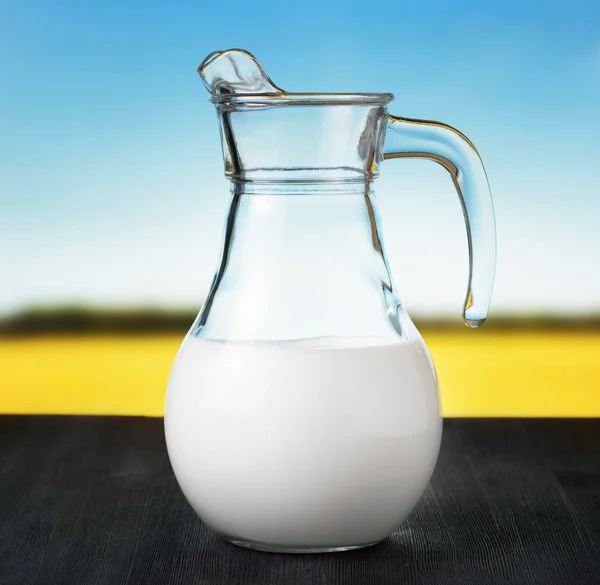 Džbán mléka na louce pozadí. půl plný džbán — Stock fotografie