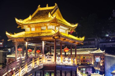 Fenghuang, Çin - 23 Eylül 2017: Phoenix Antik Kentinde geleneksel Çin mimarisinin unsurları ile muhteşem bir köprü gece görüşü. Fenghuang, Asya 'nın popüler bir turizm merkezidir..