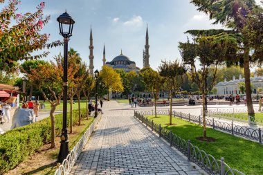 Yeşil bahçelerin arasında Sultan Ahmed Camii 'nin (Mavi Cami) muhteşem manzarası. Turistler ve halk dinleniyor ve manzaralı şehir parkı boyunca yürüyorlar..