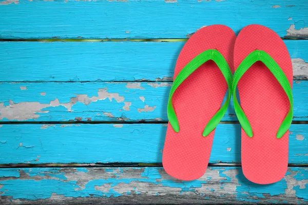 Rote und grüne Flip-Flop-Sandalen auf blauem Holz — Stockfoto