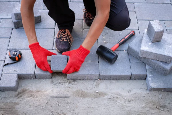 The master in yellow gloves lays paving stones — Stock Photo, Image