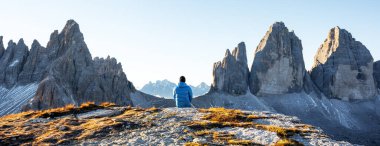 Sonbahar sezonunda Three Peaks of Lavaredo pistinde mavi ceketli turist