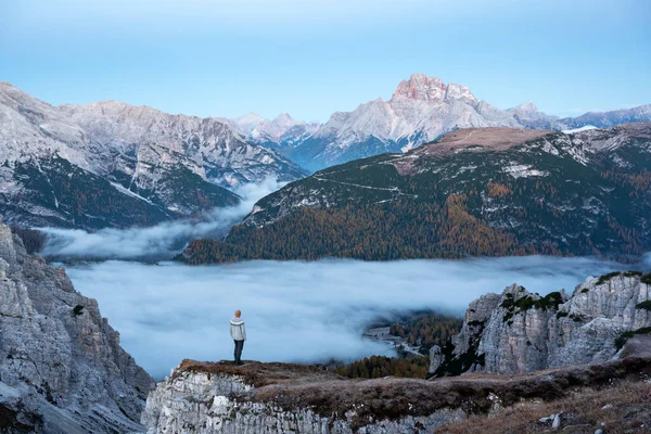 Um turista fica sobre o nevoeiro à beira de um penhasco nas montanhas Dolomitas — Fotografia de Stock